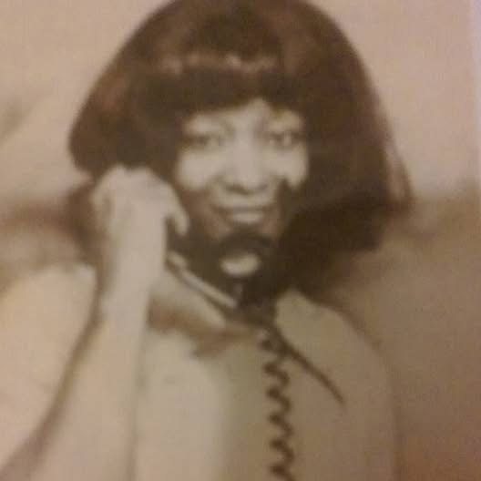 A young portrait of Joan Brunson smiling on the phone